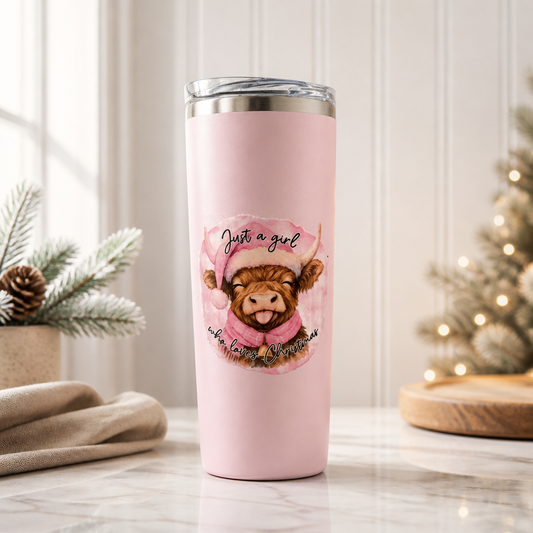 This pink, 20 oz tumbler features a printed illustration of a brown highland cow wearing a pink Santa hat and scarf, with the text 'Just a girl who loves Christmas' written around the cute cow! What a fun way to celebrate the season!